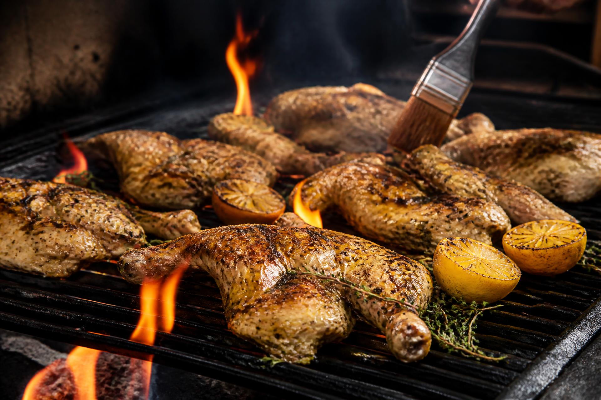 Fresh chicken halves and quarters grilling over live fire